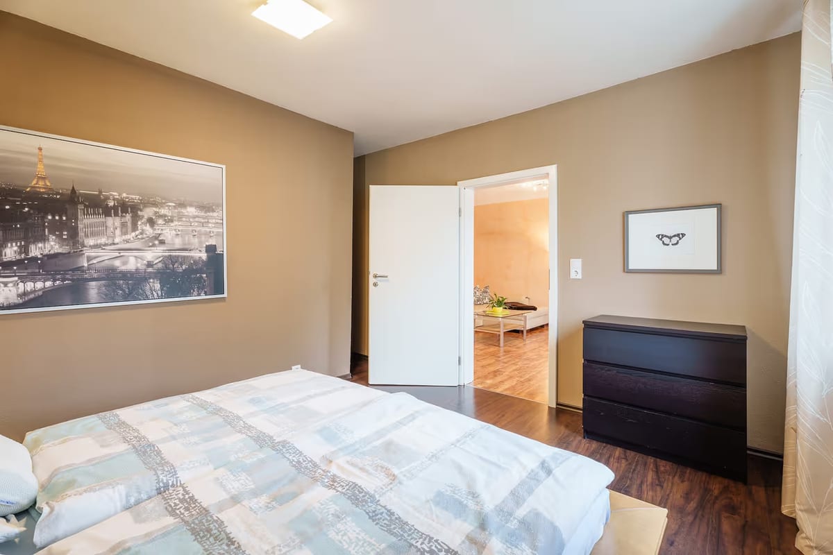 Zweites Schlafzimmer mit Kommode und offener Tür zum Wohnbereich